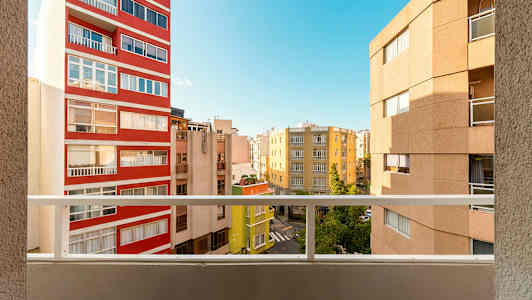 Utsikt fra en balkong med flere bygninger og en blå himmel i bakgrunnen. (AI-generert tekst)