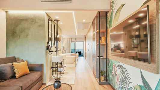 Interiøret til et stilfullt hotellrom med sofa, speil og en TV på veggen. (AI-generert tekst)