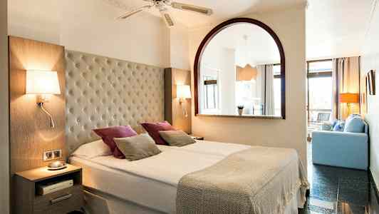 Dobbeltrom med bred seng, lamper og dekorative puter. (AI-generert tekst)