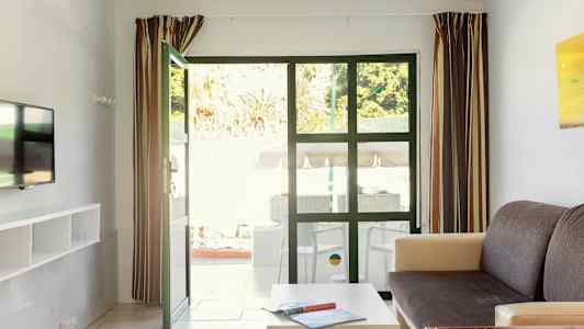 Bildet viser en stue med åpne dører til en uteplass. (AI-generert tekst)