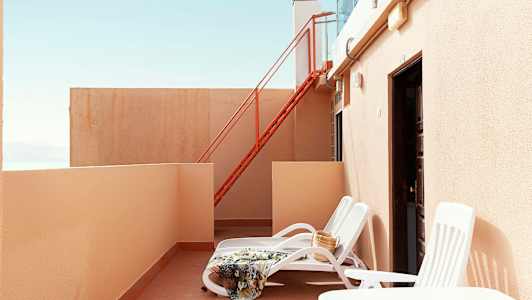 Privat terrasse med solsenger, teppe og veske. (AI-generert tekst)