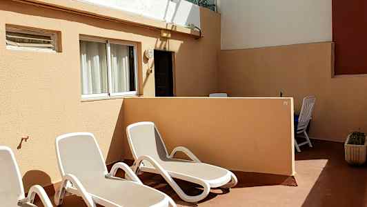 En terrasse med solsenger og bord med stoler. (AI-generert tekst)