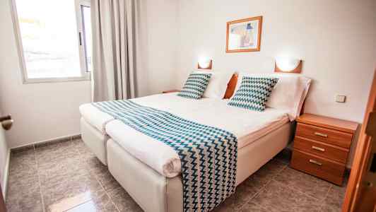 Dobbeltrom med to enkeltsenger, nattbord og vindu. (AI-generert tekst)