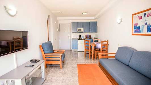 En stue med sofa, lenestol, TV og spisebord, samt en kjøkkenkrok. (AI-generert tekst)