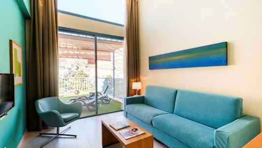 Stue med blå sofa, stol og utsikt til en balkong. (AI-generert tekst)