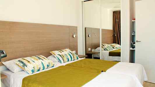 Dobbeltrom med to enkeltsenger, et speil og innredning i tre. (AI-generert tekst)