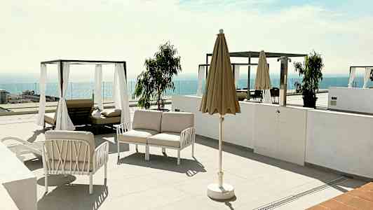 En terrasse med solsenger, parasoll og utsikt over havet. (AI-generert tekst)