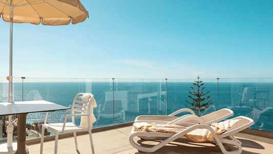 Terrasse med solsenger, parasoll og havutsikt. (AI-generert tekst)