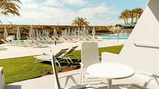 Utemøbler i solrik miljø med utsikt over solsenger ved bassenget. (AI-generert tekst)