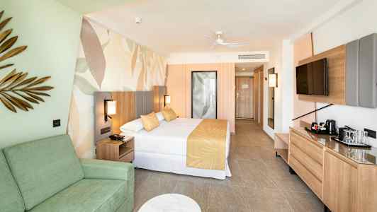 Hotellrom med seng, sofa og TV. Interiør i lyse farger. (AI-generert tekst)