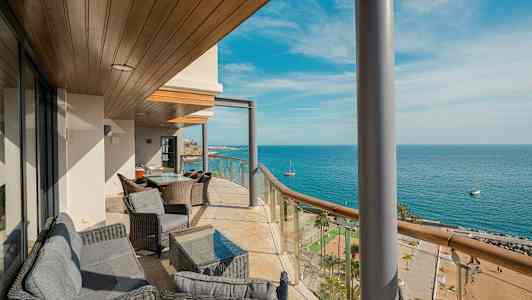 En balkong med sitteplasser og utsikt over havet og stranden. (AI-generert tekst)