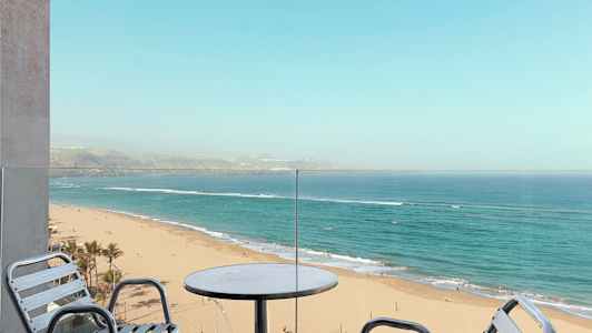 Utsikt fra en balkong mot en sandstrand og havet. (AI-generert tekst)