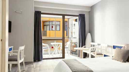 Hotellrom med to senger, sittemøbler og en balkong i bakgrunnen. (AI-generert tekst)