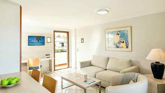 Lyst stue med sofa, lenestol, salongbord og et dekorert bilde over sofaen. (AI-generert tekst)