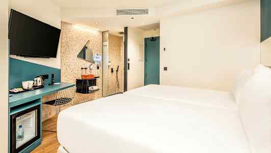 Hotellrom med seng, skrivebord og badeområde. (AI-generert tekst)