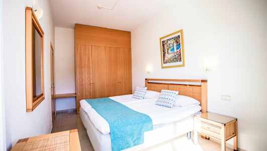 Hotellrom med en dobbeltseng, tredetaljer og et garderobeskap. (AI-generert tekst)