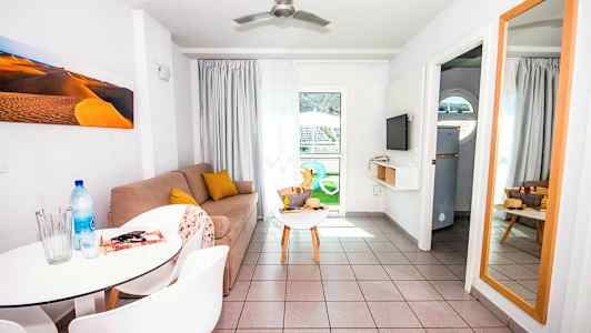 Et oppholdsrom med en sofa, et avlastningsbord, et speil og et spisebord med stoler. (AI-generert tekst)