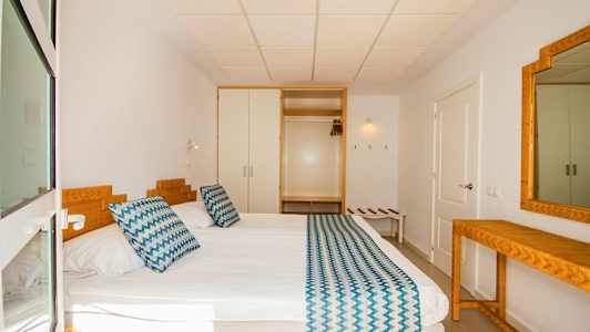 Et hotellrom med en seng, sengetøy og et speil. (AI-generert tekst)