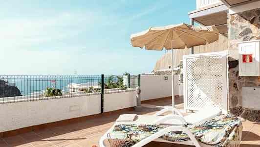 Solstol med parasoll på en terrasse med havutsikt. (AI-generert tekst)