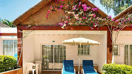 En terrasse ved en bungalow med blomster på taket. (AI-generert tekst)