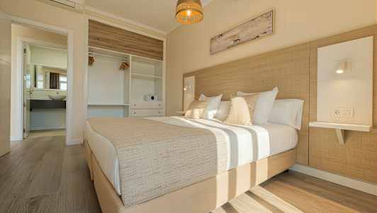 Et lyst soverom med en dobbeltseng, garderobe og åpent bad. (AI-generert tekst)