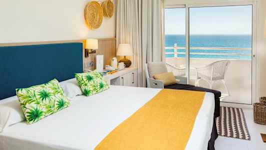 Hotellrom med dobbeltseng og havutsikt fra balkong. (AI-generert tekst)