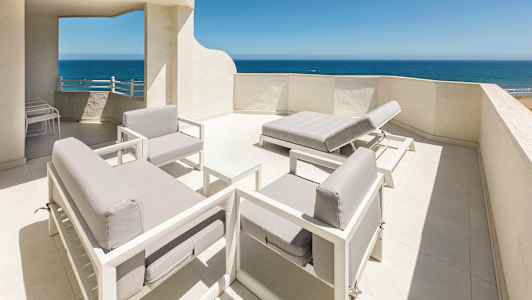 Takterrasse med hvitmalt interiør og utsikt over havet. (AI-generert tekst)