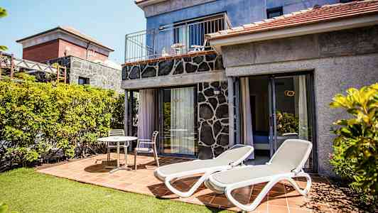 Bilde av en terrasse med solsenger og sittemøbler ved et hus. (AI-generert tekst)