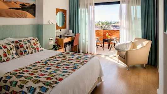 Hotellrom med dobbeltseng, sittegruppe og en balkong med utsikt. (AI-generert tekst)