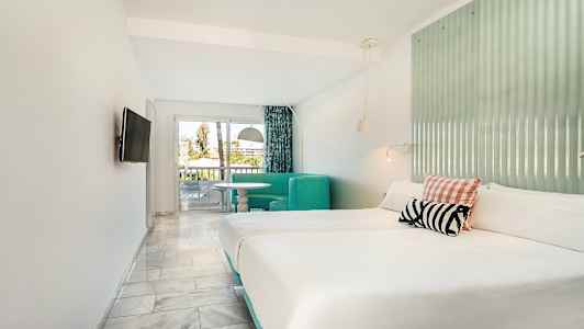 Hotellrom med dobbeltseng, sittegruppe og utgang til balkong. (AI-generert tekst)