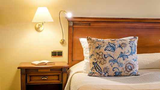 Seng med trestruktur, pyntepute og bok på nattbordet. (AI-generert tekst)