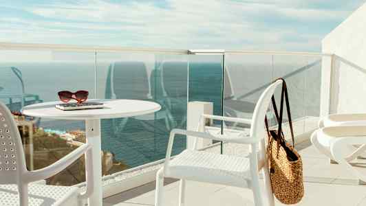 En terrasse med hvite møbler, en stråveske og havutsikt. (AI-generert tekst)