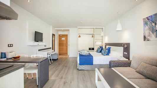 Hotellrom med seng, sofa og TV. (AI-generert tekst)