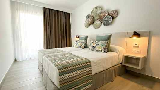 Et soverom med en dobbeltseng, pynteputer og et dekorert hodegjerde. (AI-generert tekst)