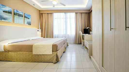 Et hotellrom med en dobbeltseng, et skrivebord og en takvifte. (AI-generert tekst)