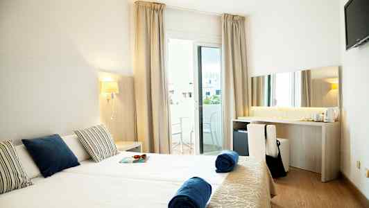 Hotellrom med to enkeltsenger, balkong og skrivebord. (AI-generert tekst)