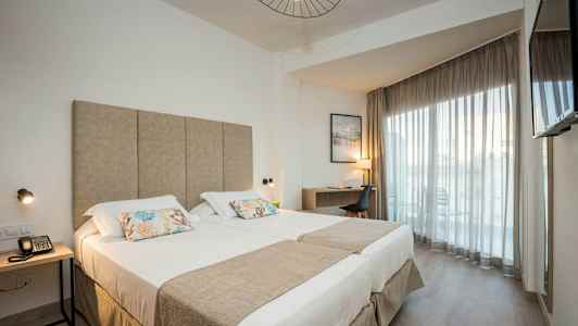 Moderne hotellrom med dobbeltseng, skrivebord og balkong. (AI-generert tekst)