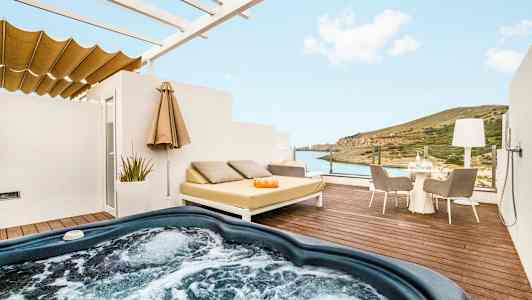 En terrasse med boblebad, liggende møbler og utsikt over havet og landskapet. (AI-generert tekst)