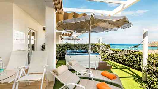 Terrasse med solsenger, parasoll, boblebad og hengekøye samt utsikt over havet. (AI-generert tekst)