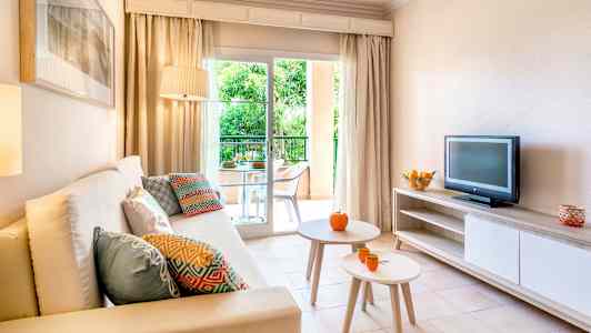 Stue med sofa, bord, TV og tilgang til en balkong. (AI-generert tekst)