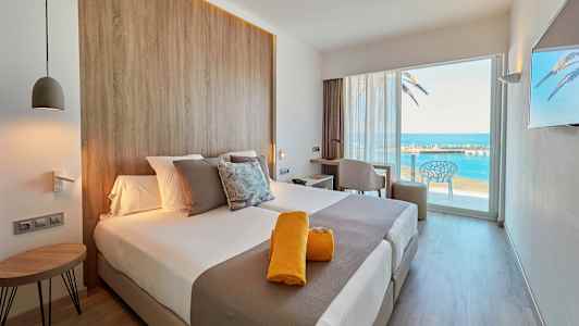 Moderne hotellrom med utsikt over havet gjennom en stor glassdør. (AI-generert tekst)