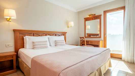 Dobbeltrom med trebord og utsikt mot en solrik balkong. (AI-generert tekst)