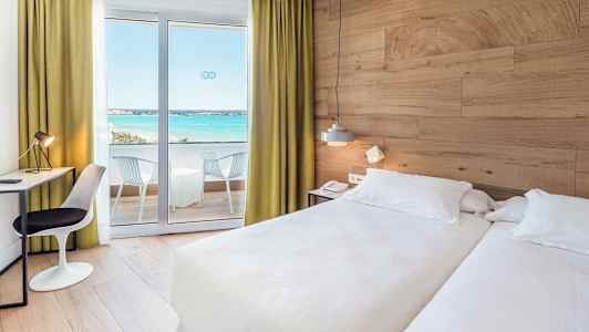 Hotellrom med to senger, skrivebord og balkong med utsikt over havet. (AI-generert tekst)