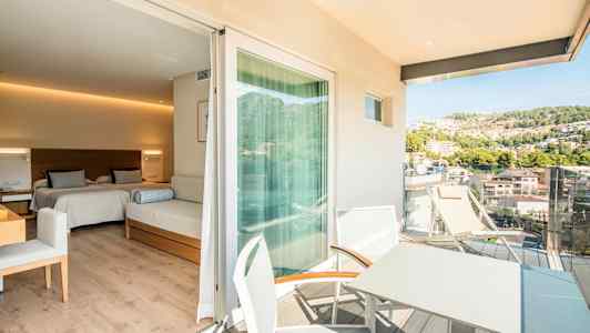 Et hotellrom med to senger og en sittemøbel, med en tilknyttet balkong hvor det finnes bord og stoler samt utsikt over en frodig ås. (AI-generert tekst)