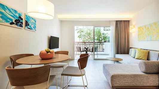 Et moderne oppholdsrom med sofa, bord og stoler, samt en balkong med utsikt. (AI-generert tekst)