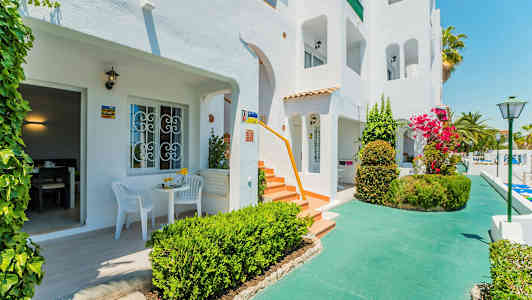 Hvit bygning med terrasser og frodig omgivelser. (AI-generert tekst)