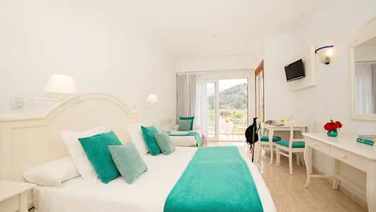 Hotellrom med hvit innredning og turkise tekstiler. (AI-generert tekst)