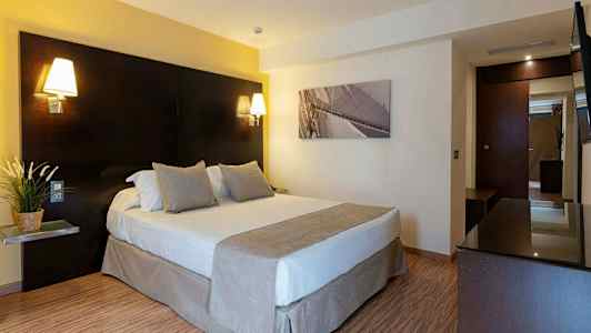 Et hotellrom med en dobbeltseng, nattlamper og et bilde på veggen. (AI-generert tekst)