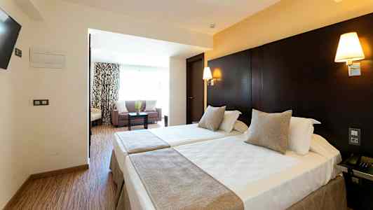 Hotellrom med to enkeltsenger og en sitteavdeling. (AI-generert tekst)