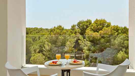 To stoler og et bord med frokost servert med utsikt over en skog. (AI-generert tekst)